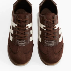 Mörkbruna sneakers med vita detaljer - Snygga mörkbruna sneakers med vita sidoränder och bruna snören, helt slutsålda. Använda 1 gång, som nya! Storlek 40, men passar även 39-41