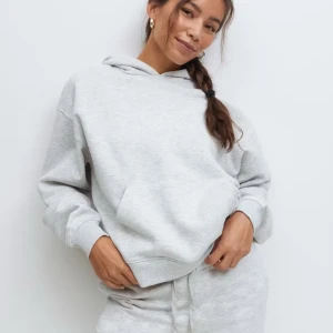 Ljusgrå hoodie från Gina Tricot - Supermjuk ljusgrå hoodie från Gina Tricot, basically basics-kollektionen. Klassisk modell med huva, magficka och ribbade muddar. Perfekt för chill dagar och enkel att matcha med allt. Oversized känsla och riktigt skön insida.
