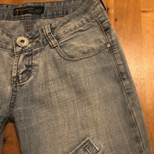 lowwaisted bootcut - Säljer ett par ljusblå bootcut jeans från Salant med coola slitna patchdetaljer på benen. Jeansen har klassisk femficksdesign, låg midja och är tillverkade i denim. Perfekta för dig som gillar en avslappnad och trendig look.