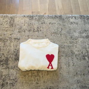 Vit stickad tröja från Ami Paris - Säljer en vit stickad tröja från Ami Paris pga jag vuxit ur den. Tröjan är i fint skick och redo för en ny ägare!