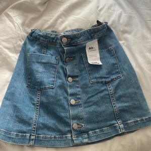 Blå jeanskjol med knappar och fickor - Snygg blå jeanskjol från Your Denim i stl 158-164 köpt i en secondhand kostat 40 kr då. Aldrig använt den.