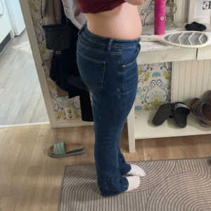 Blå bootcut jeans från Gina Tricot - Snygga blå jeans från Gina Tricot med bootcut passform och klassisk femficksdesign. Jeansen har låg midja, dragkedja och knapp framtill samt sköna stretchiga ben. Använd fåtal gånger.