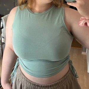 Blågrön croppad linnetopp - Snygg ljusgrön croppad linnetopp från SHEIN i storlek XL. Toppen är ärmlös och har trendiga snörningsdetaljer i sidorna som ger en cool rynkad effekt. 