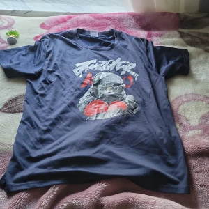 Svart t-shirt med grafiskt tryck - Cool svart t-shirt med ett stort grafiskt tryck på framsidan som visar en katt i boxarstil och text i vitt och rött. Rund hals och korta ärmar. Materialet känns mjukt och lätt, perfekt för dig som gillar streetwear och unika motiv.