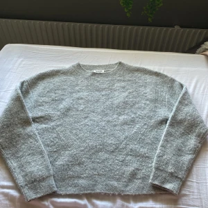 Grå stickad tröja från Kappahl - Mysig grå stickad tröja från Kappahl i storlek 146/152. Tröjan har en klassisk rund halsringning, ribbade muddar och är långärmad. Perfekt för lager-på-lager och chill dagar. Enkel och stilren design som funkar till det mesta, Aldrig använd.