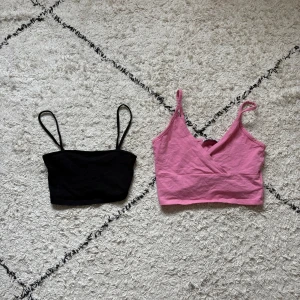 2 crop tops XS H&M Divided & FB Sister - Två croppade linne-toppar i storlek XS. En svart från H&M Divided med smala axelband och enkel design, samt en rosa från FB Sister med omlott-detalj framtill och tunna axelband. Perfekta för lager-på-lager eller till jeansshorts.