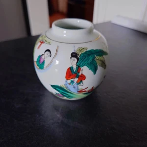Liten vad - Bilderna visar en dekorativ kinesisk porslinsvas med färgglada motiv av personer och natur. Vasen har traditionell design och är märkt 'Made in China' undertill. Perfekt som inredningsdetalj för dig som gillar asiatisk konst och kultur. 