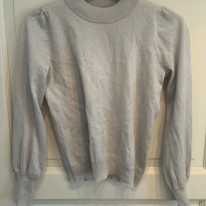 Glittrig ljusgrå tröja från STOCKH LM - Snygg ljusgrå tröja från STOCKH LM i storlek S med glittrigt material❤️❤️ Tröjan har långärmade puffärmar, ribbad hals och muddar!!