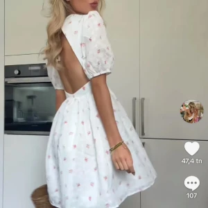 Vit blommig kortklänning med öppen rygg - Supersöt vit kortklänning med små rosa blommor, puffärmar och öppen rygg. Klänningen har en feminin passform med markerad midja och voluminös kjol. Perfekt för sommarens alla tillfällen och ger en romantisk vibe. Finns en liten fläck på ryggen men ingenting som syns supermycket.