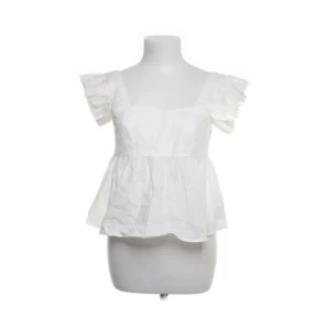 Vit volangblus från SHEIN XS - Supersöt vit blus från SHEIN i storlek XS. Toppen har volangiga korta ärmar, fyrkantig ringning och en luftig, lätt utsvängd passform. Perfekt för en fräsch och somrig look. Tillverkad i ett tunt, vävt material som känns svalt mot huden.