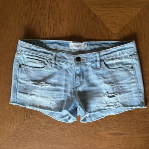 Ljusa lågmidjade jeansshorts från Abercrombie & Fitch - Såå snygga low rise shorts med slitningar från Abercrombie & Fitch! Storlek 4, passar som en M.  Midjemått: 42 cm rakt över