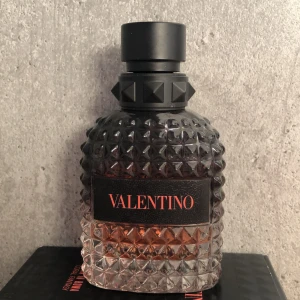 Valentino Uomo Born in Roma Coral Fantasy - Säljer en lyxig parfymflaska från Valentino, modell Uomo Born in Roma Coral Fantasy. Flaskan har en elegant design med nitar och en gradient av svart och transparent glas. Den svarta korken har en stilren look. Perfekt för den som vill ha en exklusiv doftupplevelse. I flaskan så är det ungefär 60 till 70% av parfymen av (detta kan man se på bild fyra). Den kommer med original lådan och är i toppskick. Nypris 790kr.