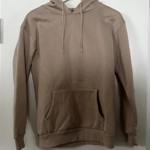 Beige hoodie med tryck - Säljer en beige hoodie med en  'Night Hunter'-design på ryggen. Tröjan har en klassisk känguruficka och justerbar huva med dragsko. Tröjan kommer från shein, tröjan är aldrig använd endast provad 