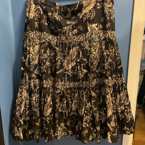 Mönstrad svart lång kjol  - En svart långkjol/ midikjol med bruna och beiga detaljer av blommor. Pris kan diskuteras