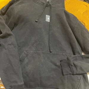 Svart hoodie med färgglatt tryck - Säljer en svart hoodie med en stor färgglad grafik på baksidan. Hoodien har en klassisk känguruficka och justerbar dragsko i huvan. 