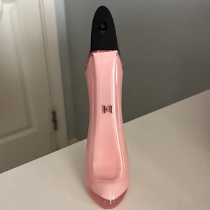 Carolina Herrera parfym - Oanvänd parfym. Elegant parfymflaska från Carolina Herrera, formad som en högklackad sko. Flaskan är ljusrosa med en svart topp och en guldig klack. Perfekt för den som älskar blommig parfym doft.