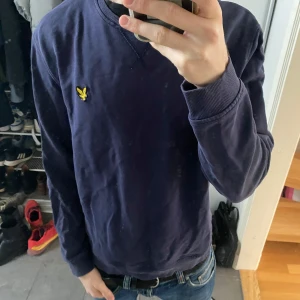 Mörkblå tröja från Lyle & Scott - Säljer en mörkblå tröja från Lyle & Scott med deras ikoniska logga på bröstet. Tröjan har långa ärmar och ribbade muddar vid ärmslut och nederkant. Perfekt för en avslappnad stil. Storleken är L men sitter mer som en M. Nytt pris: 849kr mitt pris: 249kr Hör av dig vid funderingar.