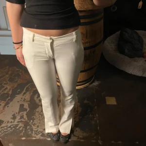 Vita Lågmidjade kostmym byxor med bootcut från bikbok - Snygga vita byxor med bootcut-stil och låg midja. De har en klassisk design med dragkedja och knappar framtill. Perfekta för en stilren look. Dom har även en slits ner till på utsida och dom är lite små i storleken brukar ha 36 men dess är lite för tajta 