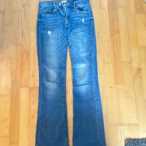 Blå bootcut jeans från ONLY - Mid waist jeans från only. Står storlek M men skulle säga att de är mer en s. De är stretchiga! 💓💓💓💓Snygga blå bootcut jeans från ONLY med slitna detaljer. De har en klassisk femficksdesign och en knappgylf. Perfekta för en avslappnad stil.