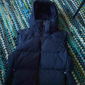 Mörkblå dun väst från Ralph Lauren - Säljer en snygg mörkblå dunväst från Ralph Lauren. Jackan har en dragkedja framtill och en hög krage för extra värme. Perfekt för kyliga dagar. Pris kan diskuteras
