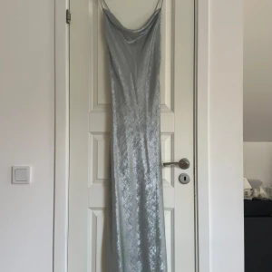 Silverfärgad långklänning med snörning - Snygg silverfärgad långklänning med glittrig finish och elegant snörning i ryggen. Perfekt för en festlig kväll eller bal! 💕