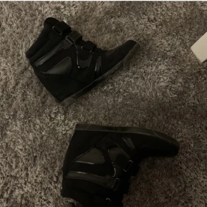 Isabel Marant liknande skor - Snygga svarta Isabel Marant liknande skor med kardborreband. Skorna har en kombination av mocka och syntetmaterial vilket ger dem en modern look. Perfekta för en stilren vardagsstil.