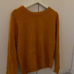 Orange stickad tröja från Vila - Säljer en snygg orange stickad tröja från Vila. Perfekt för kyliga dagar med sin mjuka och bekväma passform. Tröjan har långa ärmar och en rund halsringning.