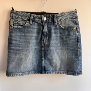 Jeanskjol från Gina Tricot  - Jeanskjol från Gina Tricot i klassisk blå denim. Kjolen har en kort längd med femficksdesign och knappstängning fram. 