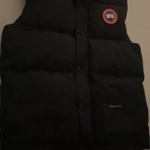 Mörk blå dunväst från Canada Goose - Säljer en mörkblå dunväst från Canada Goose som inte kommer till användning skicket är 9/10 och inga fel på den. Strl L 