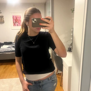 Svart kortärmad topp - Säljer en stilren svart kortärmad topp. Perfekt för en enkel och klassisk look. Passar bra till jeans eller kjol. Passar både M och L