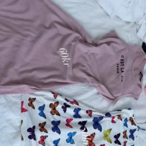 Tre klänningar med olika mönster och färger - Säljer tre snygga klänningar . Ett rosa med text, ett vitt med färg fjärilar och ett grönt. Perfekta för sommaren. Alla tre ärmlösa och i mjukt material.