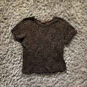 Brandy meville crop top - Säljer en cool leopardmönstrad topp med korta ärmar. Perfekt för att ge din outfit en vild touch. Toppen har en rund hals och är i en mjuk och bekväm kvalitet.