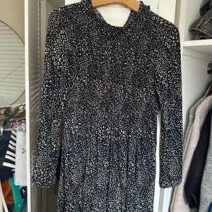Mönstrad klänning från Zara - Säljer en snygg mönstrad klänning från Zara i mörkblått med ljusa prickar. Klänningen har långa ärmar och en elegant passform som passar perfekt för olika tillfällen. Perfekt för dig som vill ha något stilrent och trendigt i garderoben.
