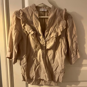Beige blus med refflar - En snygg beige blus från Holly and white. Mycket bra skick behöver bara strykas. Den är i storlek xs men passar även S. Passar mycket bra nu till sommaren.