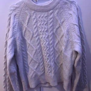 Vit stickad tröja från Gina Tricot - Original pris är 400 men säljer för 200. Mysig beige  stickad tröja från Gina Tricot med flätmönster. Perfekt för kyliga dagar med sin klassiska design och ribbade kanter. Ett måste i garderoben för en stilren look.