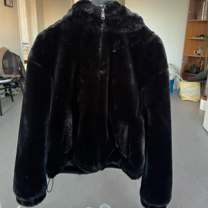 Svart pälsjacka med dragkedja - Säljer en supermjuk och fluffig svart pälsjacka med dragkedja. Jackan har långa ärmar och en hög krage för extra värme. Perfekt för kyliga dagar när du vill känna dig både stilren och bekväm. 