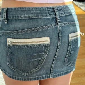 Jeanskjol med dragkedjor - Trendig jeanskjol i blå denim med snygga dragkedjor på bakfickorna. Kjolen har en kort längd och klassisk femficksdesign med bälteshällor. Perfekt för en avslappnad stil. Bilder från den tidigare säljaren, säljer då den är för stor för mig. Men skriv gärna om fler bilder behövs eller liknande! Den är 42 cm rakt över och 29 cm på längden, super fin tills i sommar!! ☀️💕