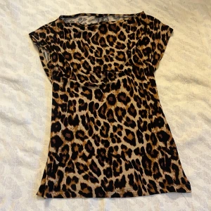 Leopardmönstrad topp - Snygg leopardmönstrad topp med korta ärmar. Perfekt för att ge din outfit en djärv touch. Tillverkad i ett mjukt och bekvämt material som känns skönt mot huden. Passar både utekvällar och vardagen. En lapp är avklippt.