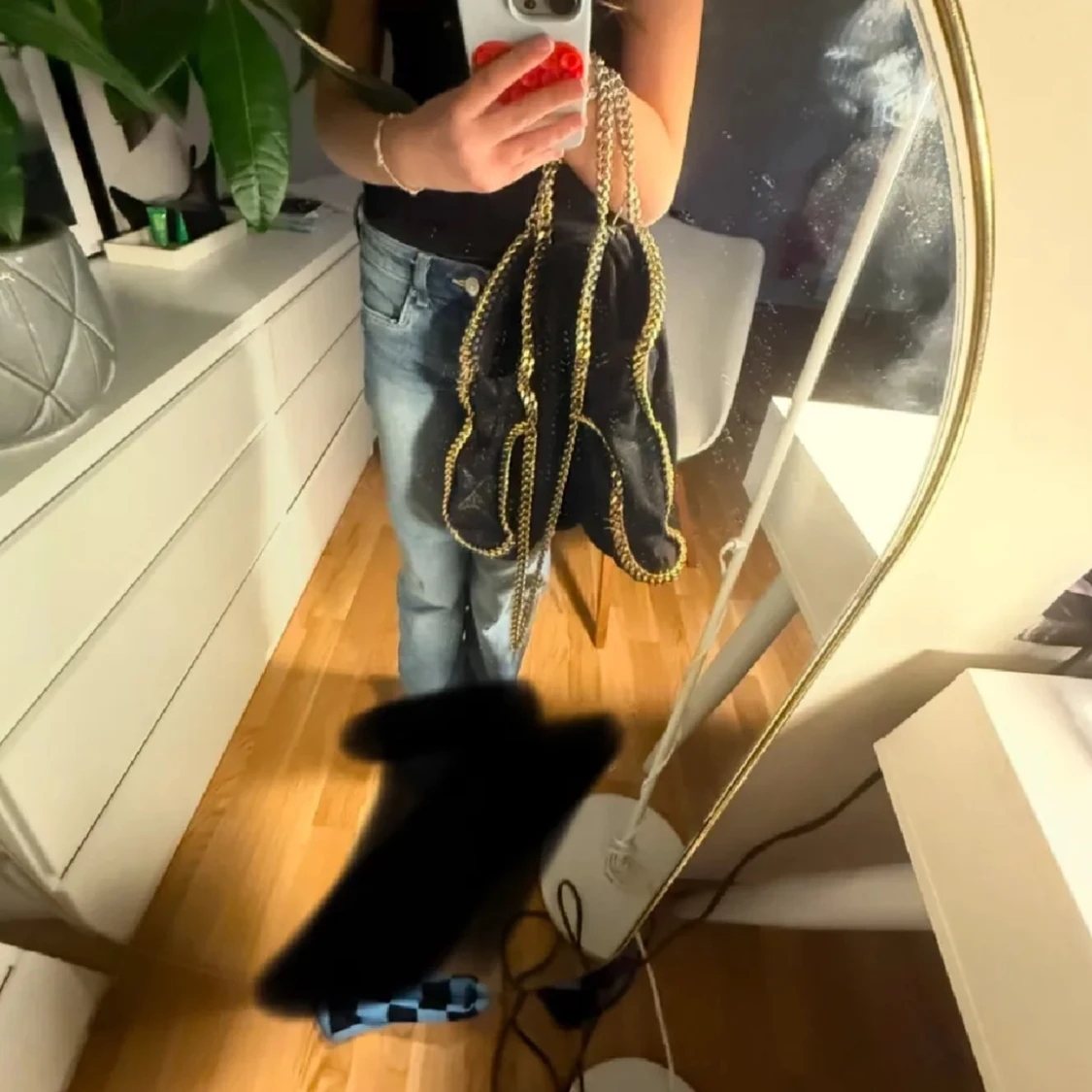 Svart axelväska med kedjedetaljer kan mötas upp