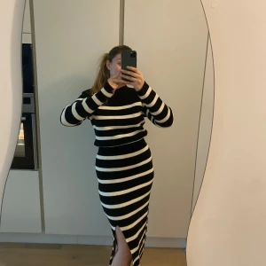 Svartvit randig stickad klänning från Adoore 🖤 - Säljer min svartvit stickade klänning från Adoore i stl 40. Klänningen har lång ärm, hög hals och en slits framtill. Den är figurnära och går in i midjan, även vadderade axlar. Perfekt för dig som gillar en stilren och trendig look. Använd ett fåtal gånger och är i finfint skick!