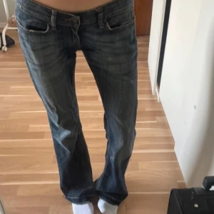 Blå bootcut jeans - Säljer ett par klassiska blå bootcut jeans med låg midja. Jeansen har en lätt tvättad look och fem fickor. Perfekta för dig som gillar en avslappnad och tidlös stil.
