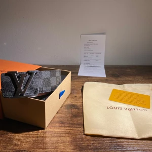 Svart bälte - Fint svart rutigt bälte som har en silvrig logga. Man får box oxh kvitto, allt man behöver. Aldrig använd helt nytt 