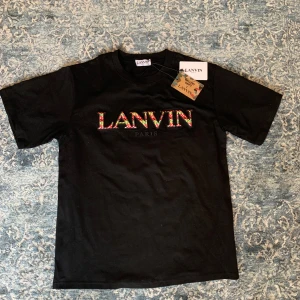 Lanvin t-shirt  - Säljer en svart t-shirt från Lanvin i samarbete med Gallery Dept. Den har endast testats och är sprillans ny. Storlek M men den är lite stor i storleken, Perfekt med en unik touch till din outfit. Hör av er vid funderingar🙌
