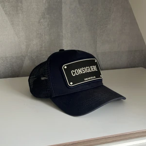 John Hatter & Co   Consigliere  Mörkblå - Snygg mörkblå keps från John Hatter & Co med en Consigliere text. Kepsen har mesh på sidorna och justerbar snapback baktill. Mycket bra skick, ej använd under träning eller liknande endast några gånger till vardags. Har inte huggit fast priset i en sten 🪨 