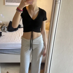 Svart croppad ribbad topp från FB Sister - 25kr Säljer en svart croppad topp från FB Sister i ribbat material. Toppen har korta ärmar, v-ringning och knyt framtill som ger en snygg detalj. Perfekt till jeans eller kjol för en trendig look.