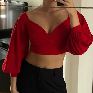 Röd croppad topp med ballongärmar - Trendig röd croppad topp med djup v-ringning och ballongärmar. Toppen har är perfekt för att skapa en snygg och modern look. Varm röd färg! Jättesnygg på sommaren! 