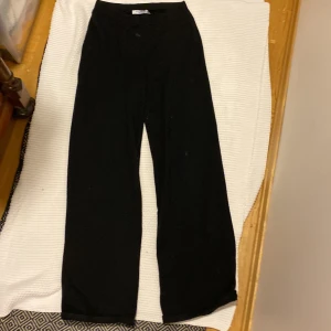 Svarta vida byxor från NA-KD - Svarta byxor från NA-KD med en rak och vid passform. Byxorna har hög midja och är tillverkade i ett mjukt material som känns bekvämt mot huden. Perfekta för en avslappnad och stilren look. Noppiga