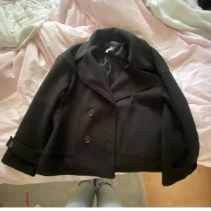 Svart kappa från Design by Sí - Säljer den virala kappan från Design by Sí i svart, jätte fint skick! Storlek XS/S skulle säga att den passar folk som bär XS-M. Inte för varm men inte för kall samtidigt ⛄️☕️ Passa på och köp när det är fri frakt nu 💖lite nopprig men inget man tänker på 