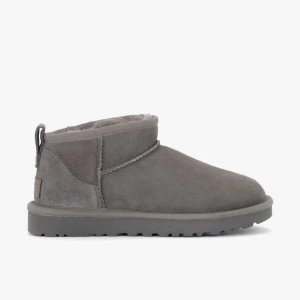 Gråa boots från UGG - Gråa boots från UGG i mocka med mjukt foder och platt sula. Klassisk rund tå och låg modell med dragflik bak. Perfekta för kyliga dagar.