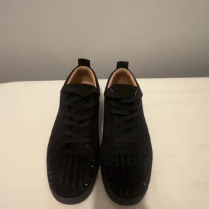 Svarta sneakers  från Christian Louboutin - Hej Säljer ett par svarta sneakers från Christian Louboutin med svarta spikar på tån och klassisk röd sula. Har inte låda 